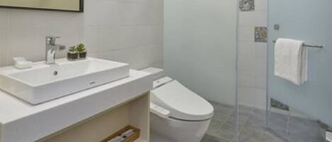 Un baño moderno con un espejo grande, dos lavamanos, un inodoro y una ducha con cerramiento de vidrio.