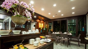 A well-lit dining area with a buffet setup, including a variety of dishes and a decorative orchid centerpiece. - Huern Na Na Boutique Hotel (Phrae)