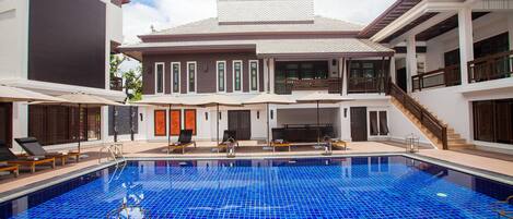 Un hotel con una amplia piscina cubierta, varios balcones y una zona de estar techada al aire libre.