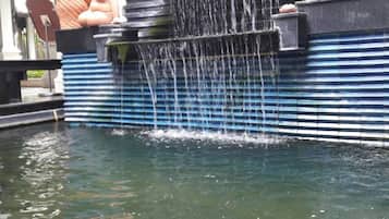 Un estanque de koi con una cascada y estatuas decorativas.