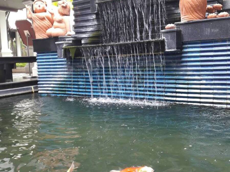Un estanque de koi con una cascada y estatuas decorativas.