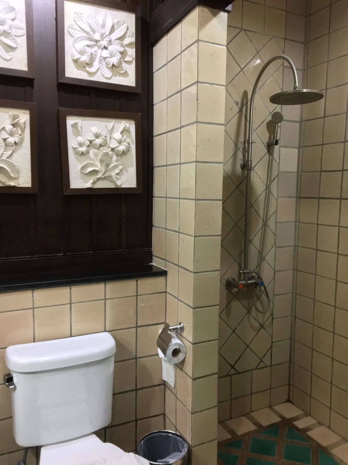 A bathroom with a toilet, a shower, and decorative wall panels.