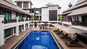 A hotel with a central swimming pool, multiple balconies, and outdoor seating areas. - Huern Na Na Boutique Hotel (Phrae)