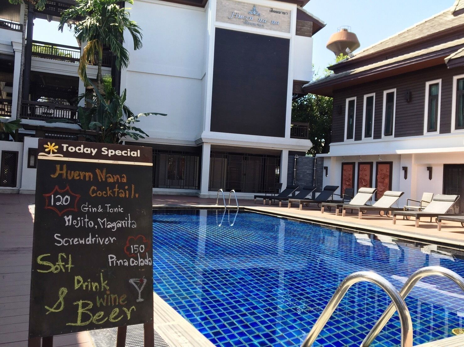A poolside area with a sign listing a 'Today Special' menu including a cocktail and drinks.