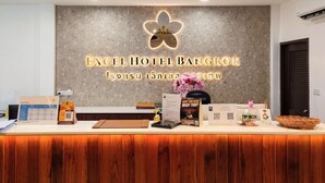 Un comptoir d’accueil d’hôtel au design moderne, agrémenté d’un logo et doté de divers supports d’information.