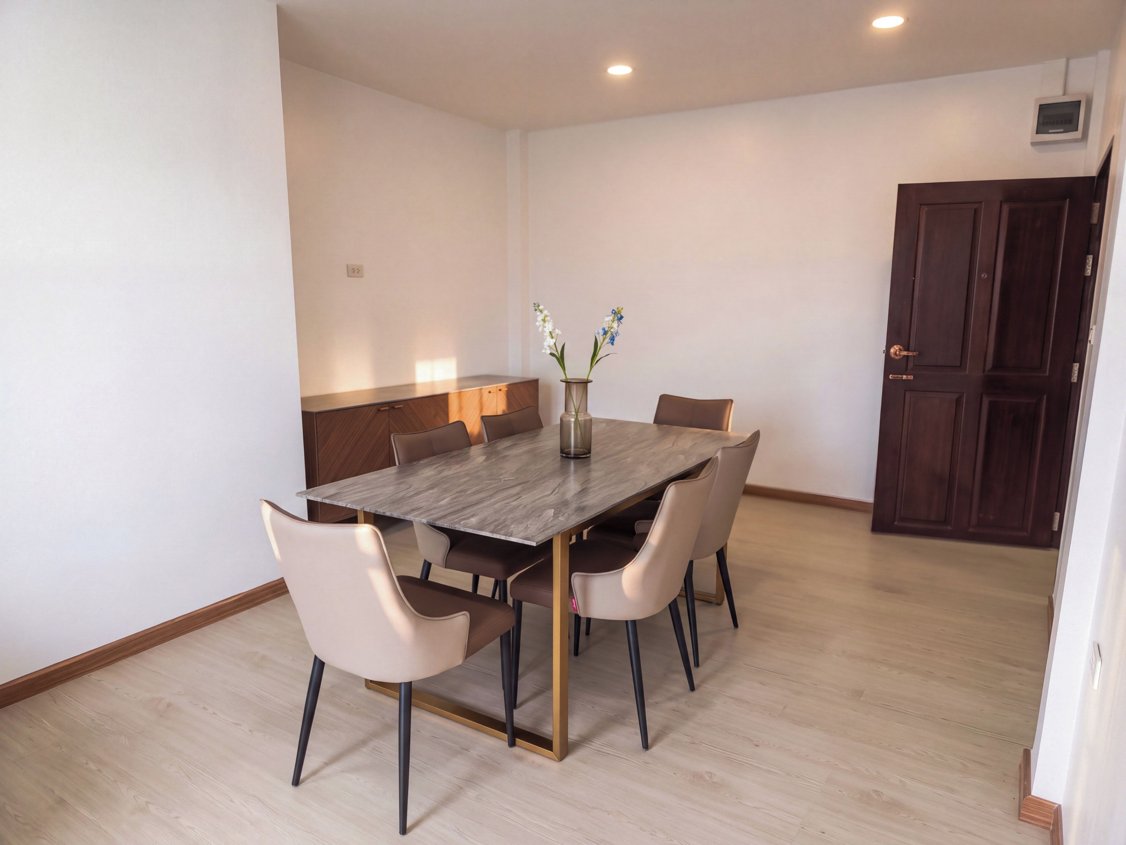 A dining area with a rectangular table, six chairs, and a vase with flowers.