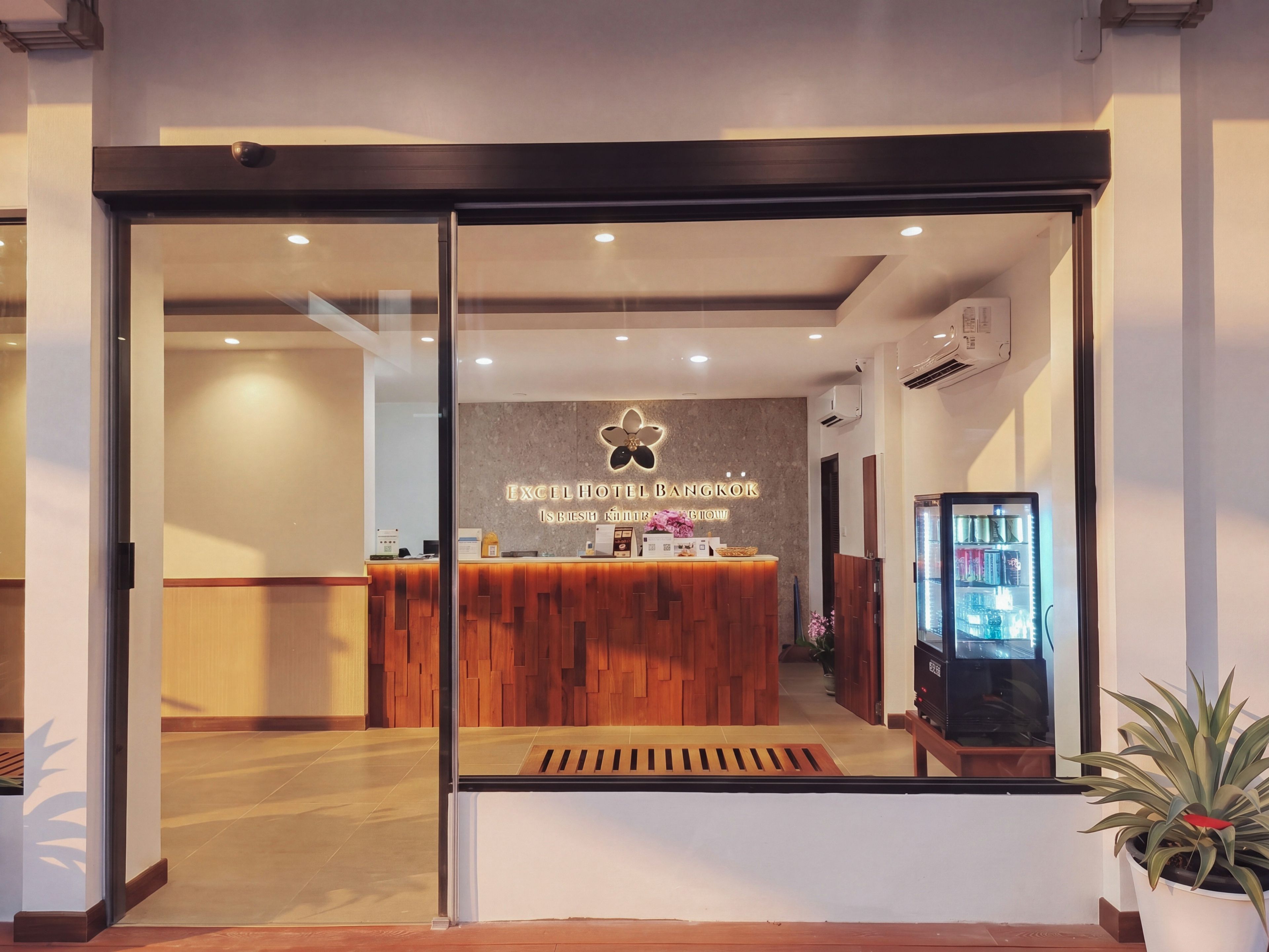 Zona de recepción de hotel con mostrador de madera, un cartel en la pared y una máquina expendedora.