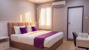 Een slaapkamer met een bed, nachtkastje, stoel, bureau en een airconditioning.