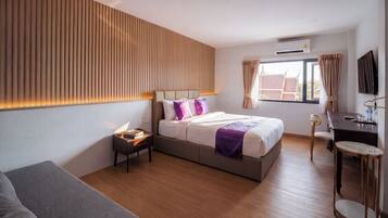 A modern hotel room with a bed, bedside table, and a desk with a chair.