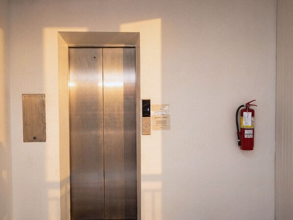 An elevator with a fire extinguisher mounted on the wall to its right. - Excel Hotel Bangkok (Bangkok)