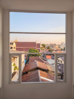 Une vue depuis une fenêtre donnant sur un paysage urbain, avec des immeubles et un temple.