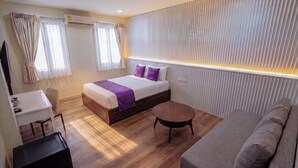 Une chambre d’hôtel moderne équipée d’un lit, d’un canapé, d’un bureau et d’une petite table.