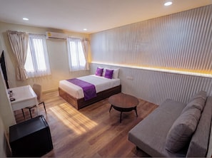 Une chambre d’hôtel moderne équipée d’un lit, d’un canapé, d’un bureau et d’une petite table.
