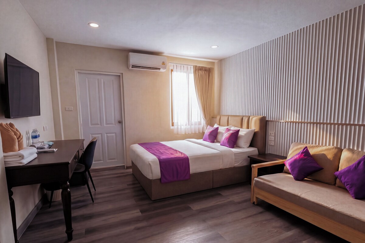 A hotel room with a bed, a sofa, a desk, and a TV.