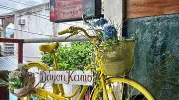 A yellow bicycle with a basket and a sign reading "Dayon Kamo" parked outside a building with a sign for "Tan-woo Restaurant".