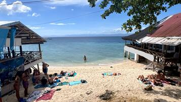 A beach with a wooden structure, a pier, and a clear view of the ocean.