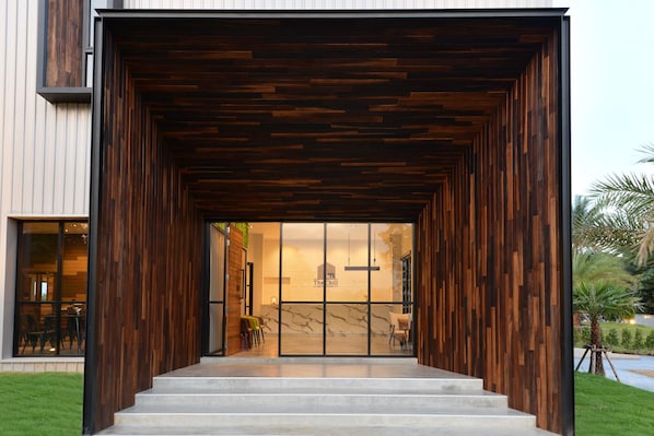 A modern building with a wooden facade, a glass entrance, and a staircase leading to the interior.