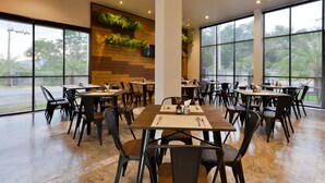 Een ruim restaurant met grote ramen, houten paneelwanden en plafondventilatoren.