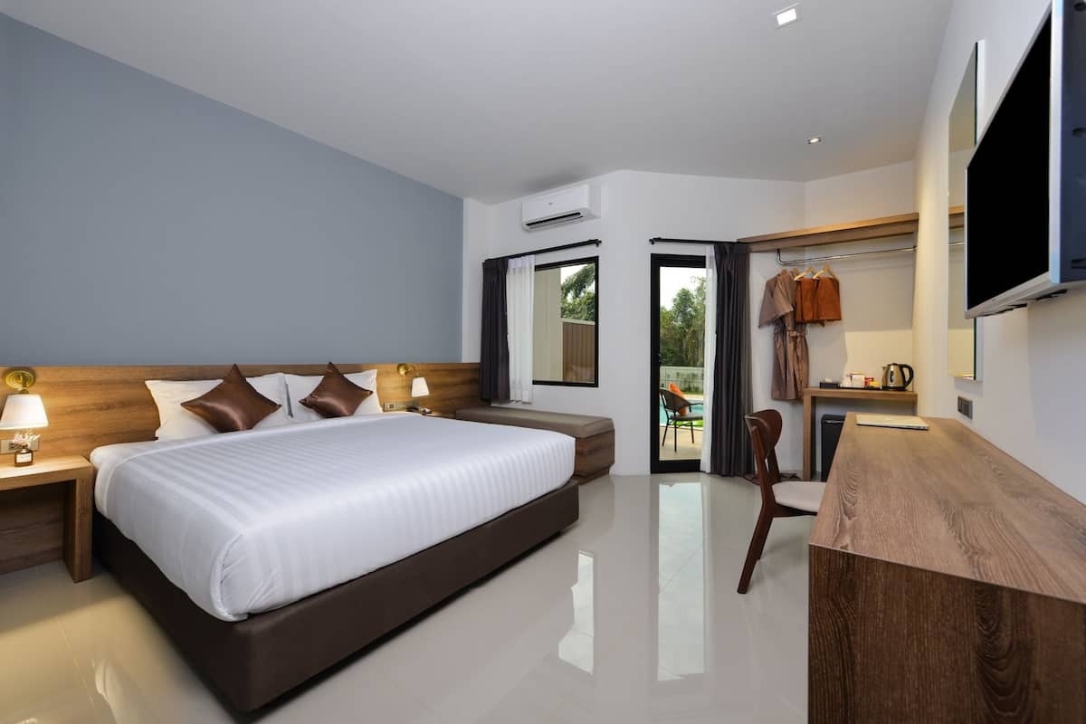 A modern hotel room with a large bed, bedside tables, a desk, and a TV mounted on the wall.