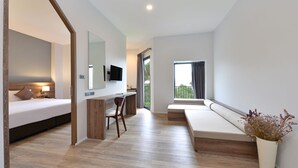 Een moderne hotelkamer met een bed, bureau en zithoek.