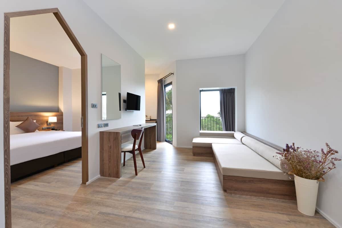 A modern hotel room with a bed, desk, and seating area.
