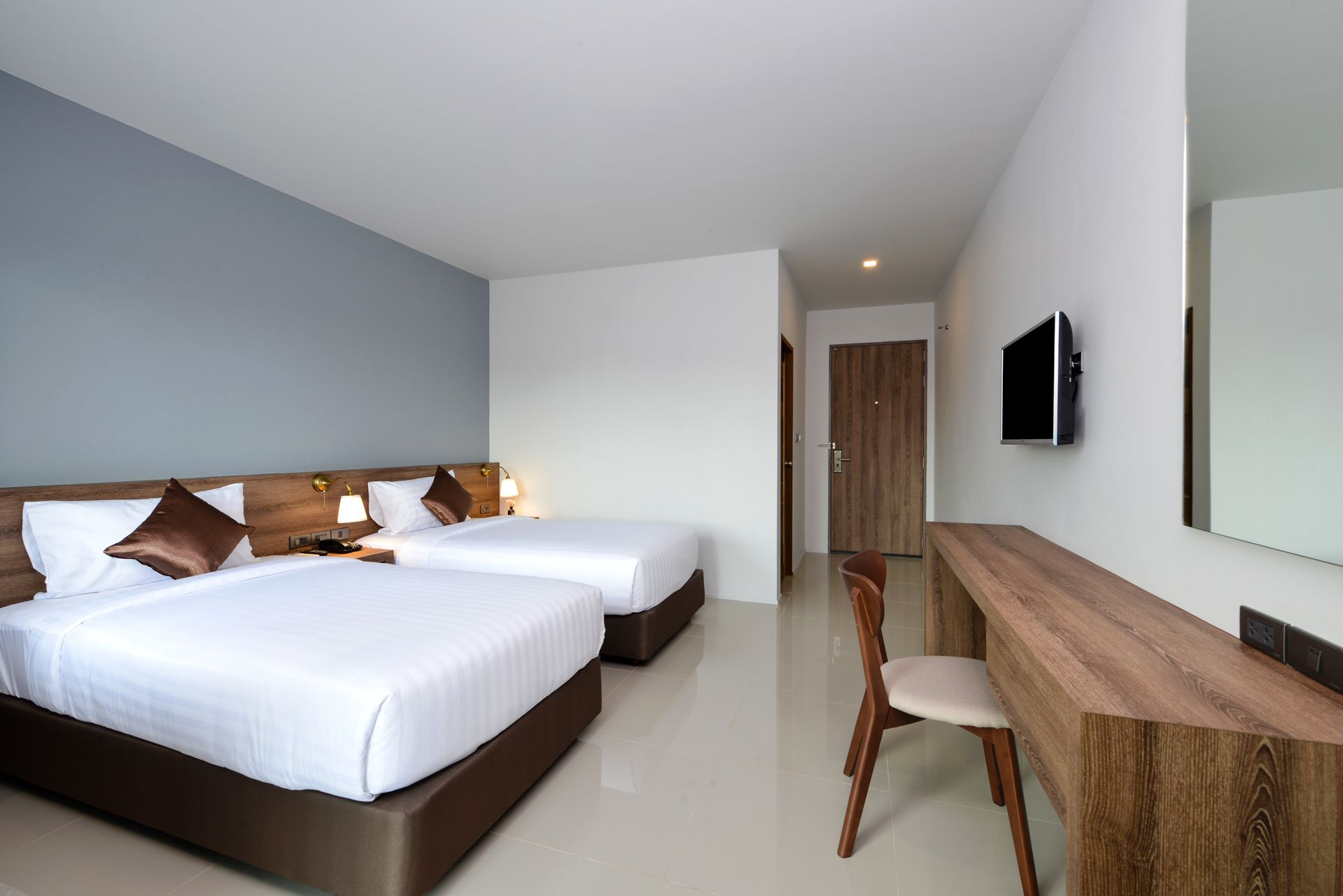 Une chambre d’hôtel avec deux lits, un bureau, une chaise, une télévision et une porte.