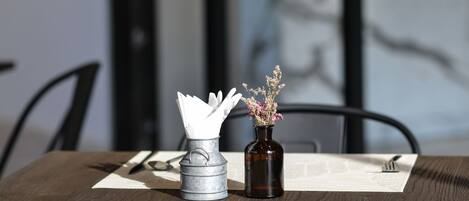 Ett matbord dukat med en vas med blommor, en servettställ och bestick på en bordsdekoration.