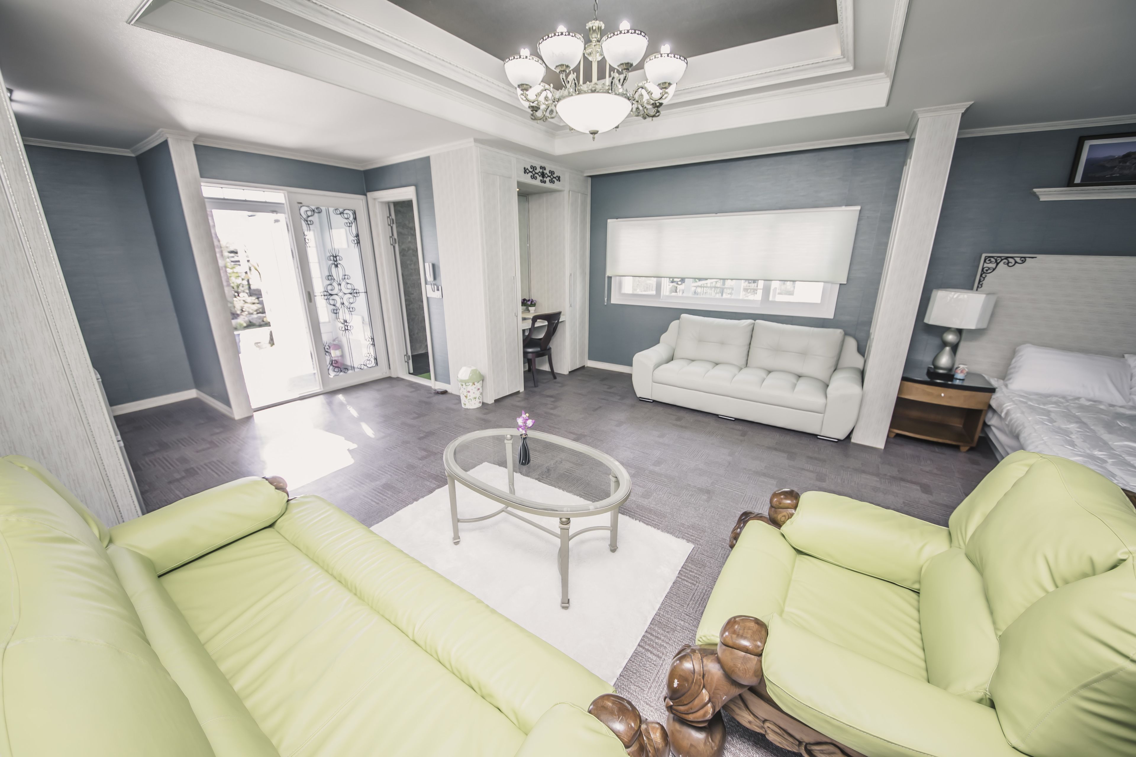 A spacious living room with a large sofa, a coffee table, and a chandelier.