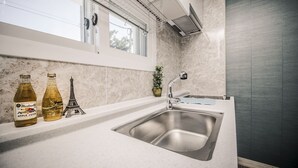 Una cocina con un lavamanos de acero inoxidable, una ventana sobre el lavamanos y una planta en maceta en la encimera.