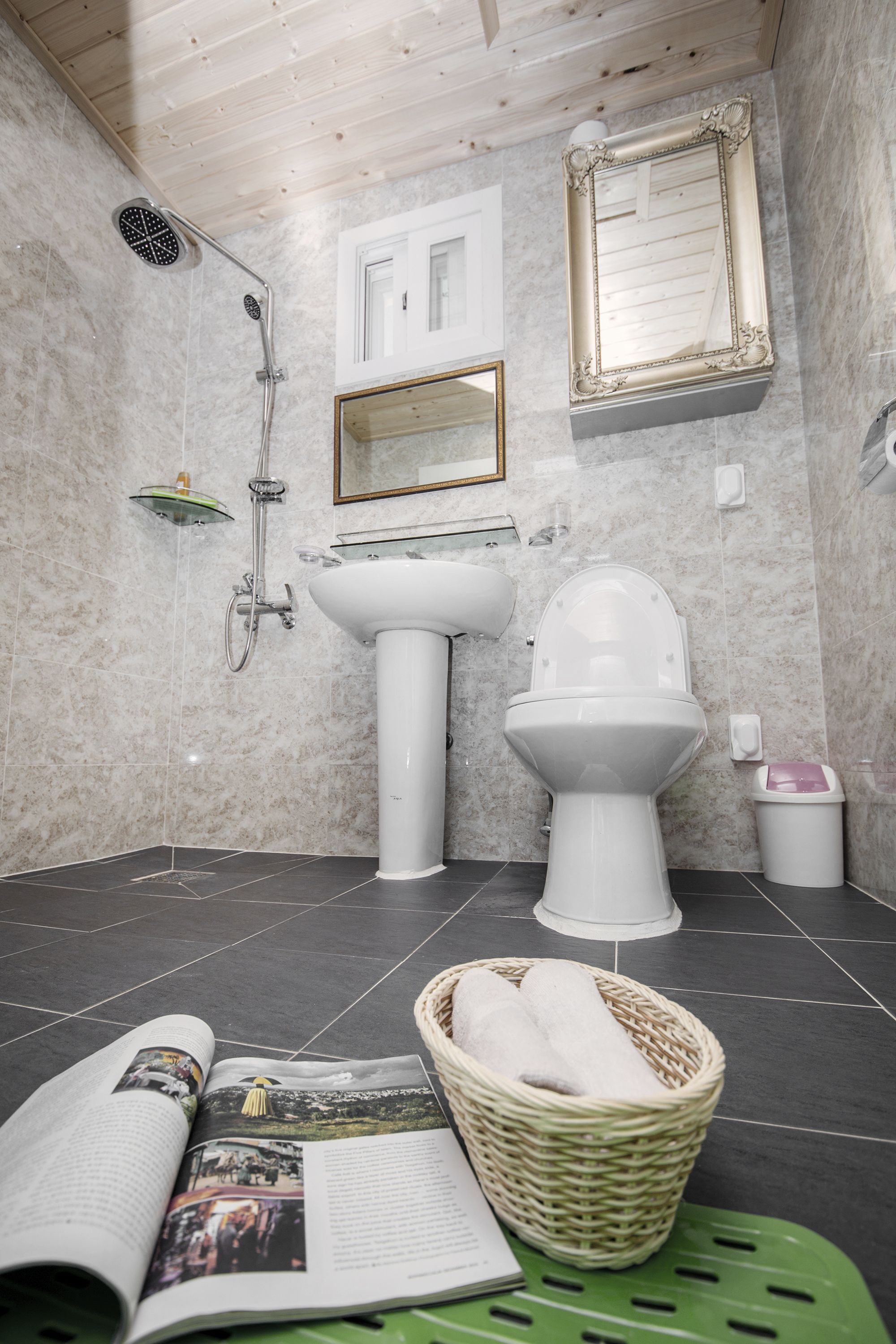 A bathroom with a shower, sink, toilet, and a wicker basket with towels.