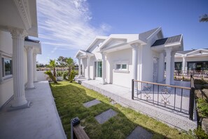 A modern residential building with white columns, a covered patio, and a well-maintained lawn. - Jeju Washington (Seogwipo)