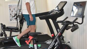 A gym with a treadmill, a stationary bike, and a weight bench.