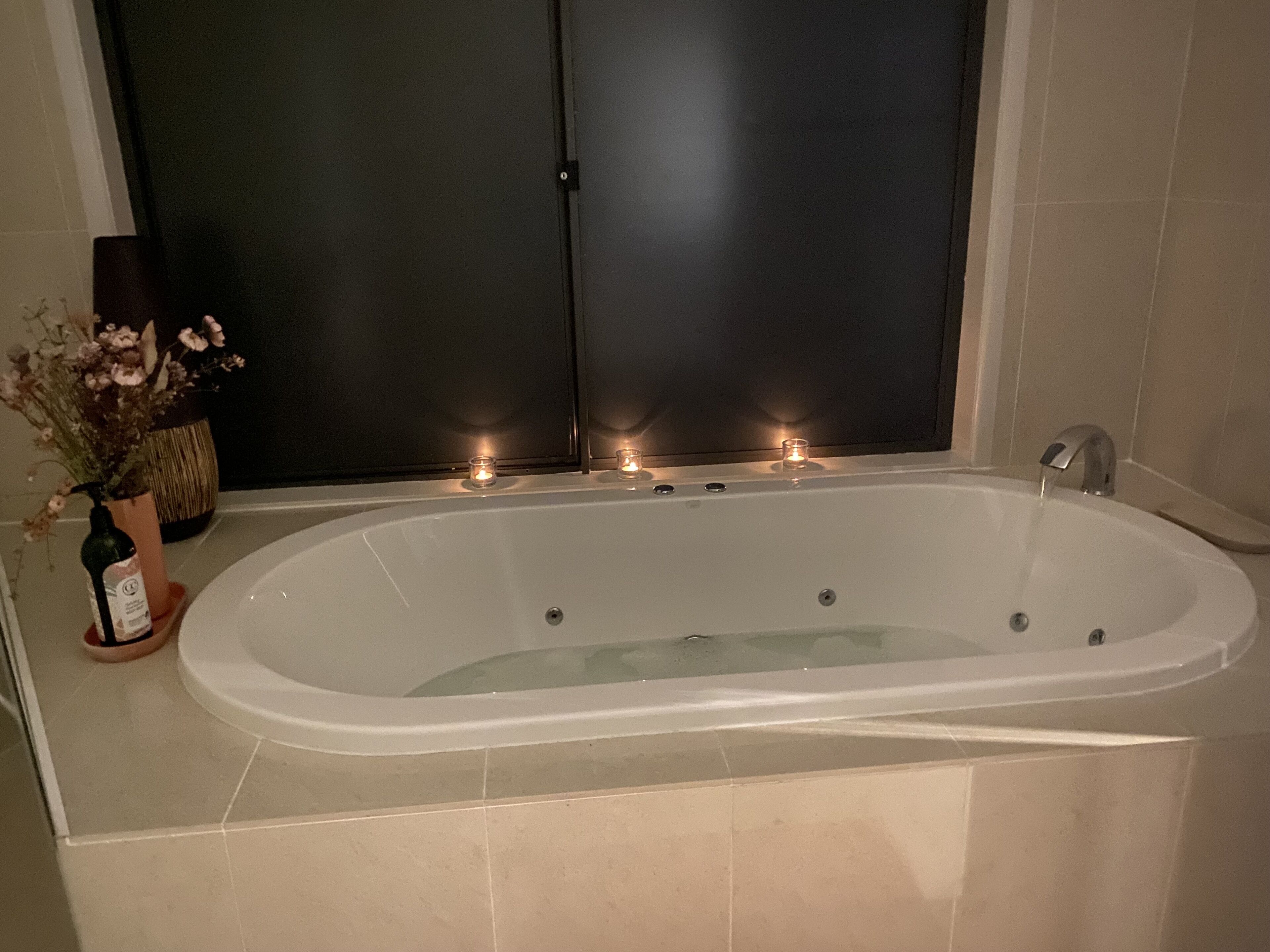 A large, oval-shaped bathtub with a faucet on one side, surrounded by beige tiles.