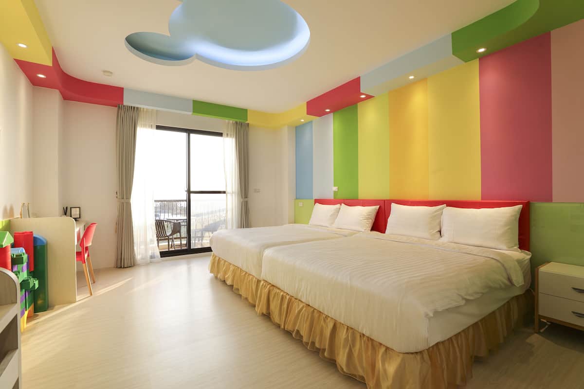 Quarto de hotel moderno com duas camas, varanda e vista para a cidade.