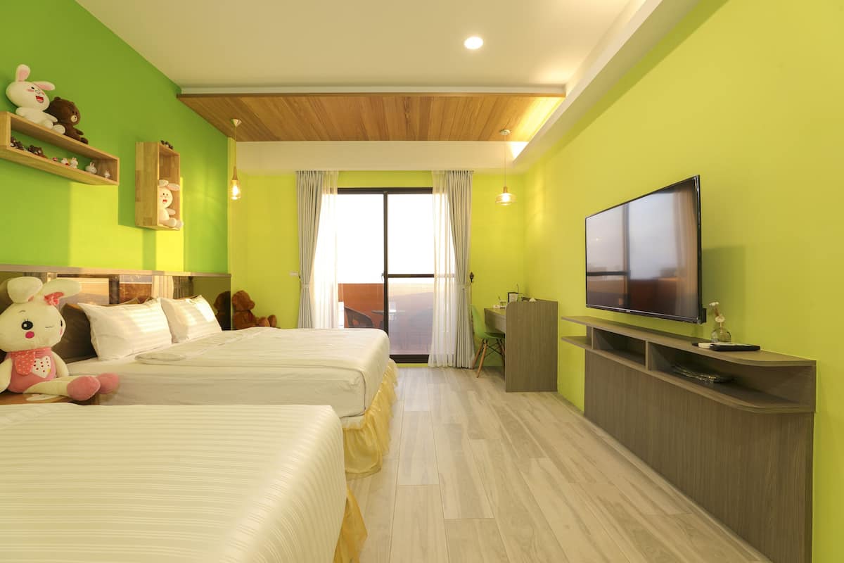 Quarto de hotel com duas camas, televisão, escrivaninha e varanda com vista.