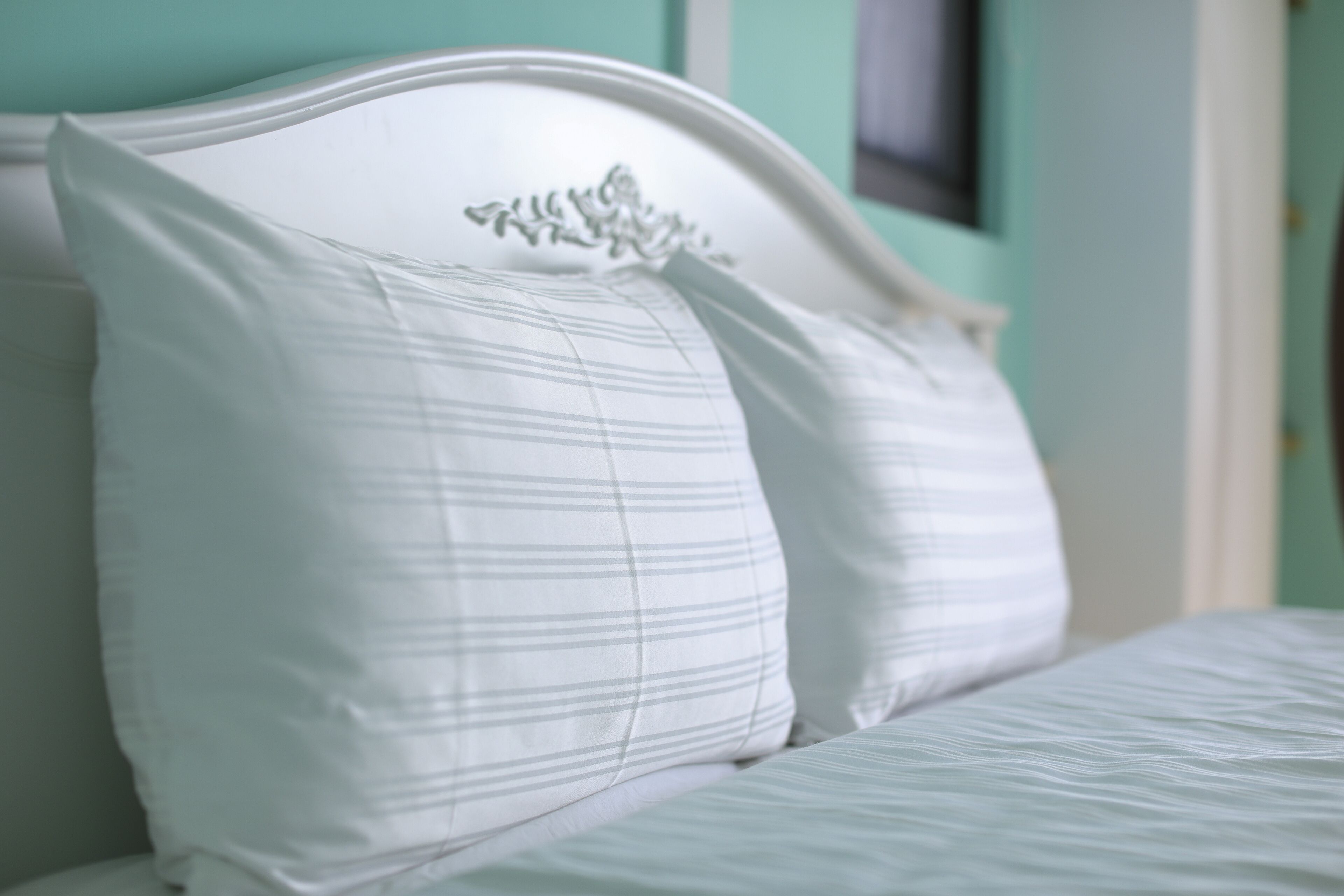 A bed with white bedding and a white headboard with a decorative crest.