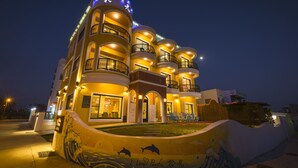 A multi-story hotel with balconies, a swimming pool, and a mural with dolphins. - Shiguang B&B (Magong)