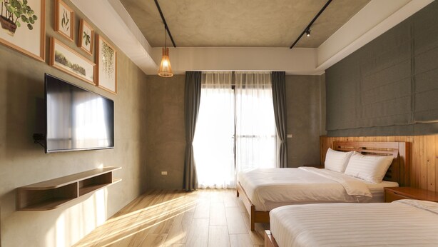 A modern bedroom with two beds, a flat-screen TV, wooden flooring, and a large window with curtains. - Shiguang B&B (Magong)