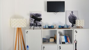 A room with a telescope, a television, and framed artwork on the wall. - Aphrodite Studios (Kalymnos)