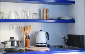 A kitchen with a stove, kettle, and utensils on the counter. - Aphrodite Studios (Kalymnos)