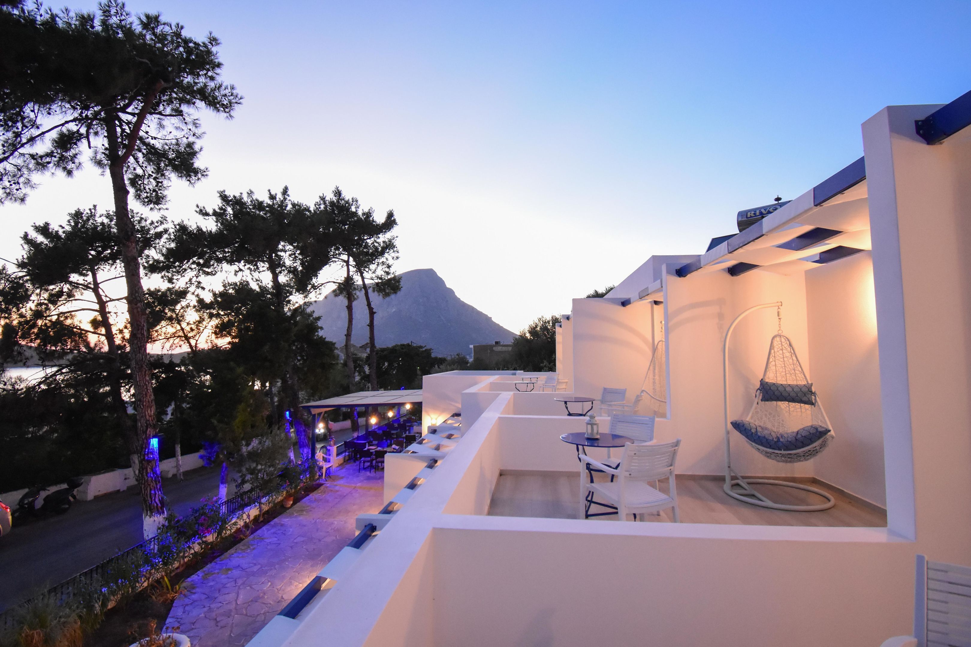 A modern outdoor seating area with white furniture, a hanging chair, and ambient lighting.