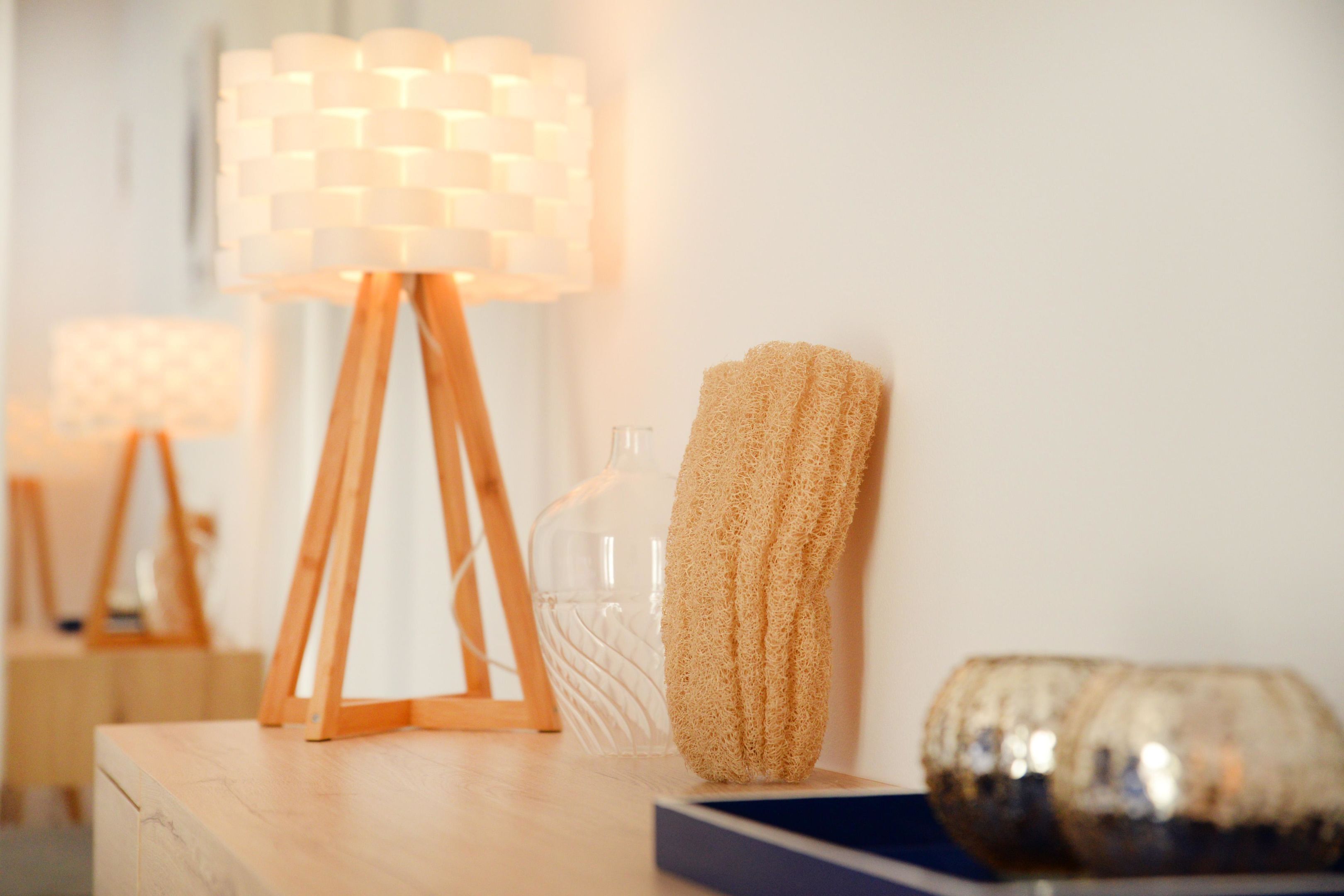 A wooden table with a lamp, a sponge, and a decorative glass object.