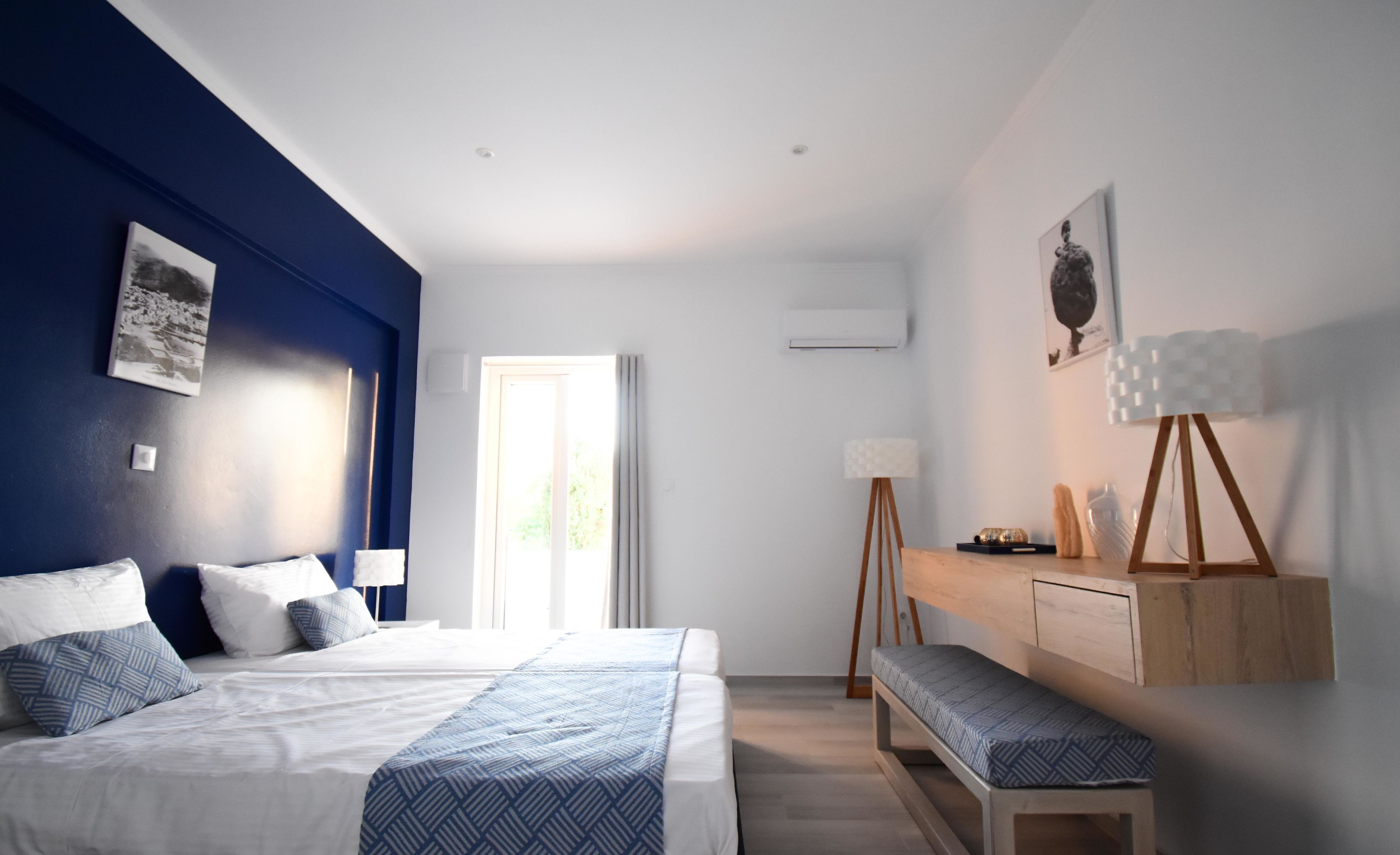 Une chambre moderne avec un grand lit, des tables de chevet, un bureau et un banc.