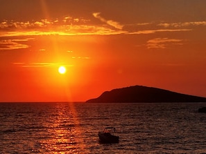 Un atardecer sobre un cuerpo de agua con un barco y una isla distante.