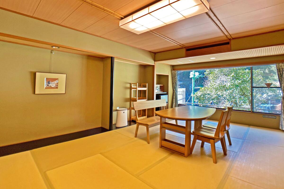 Habitació tradicional japonesa amb sòls de tatami, una taula de fusta baixa i cadires.