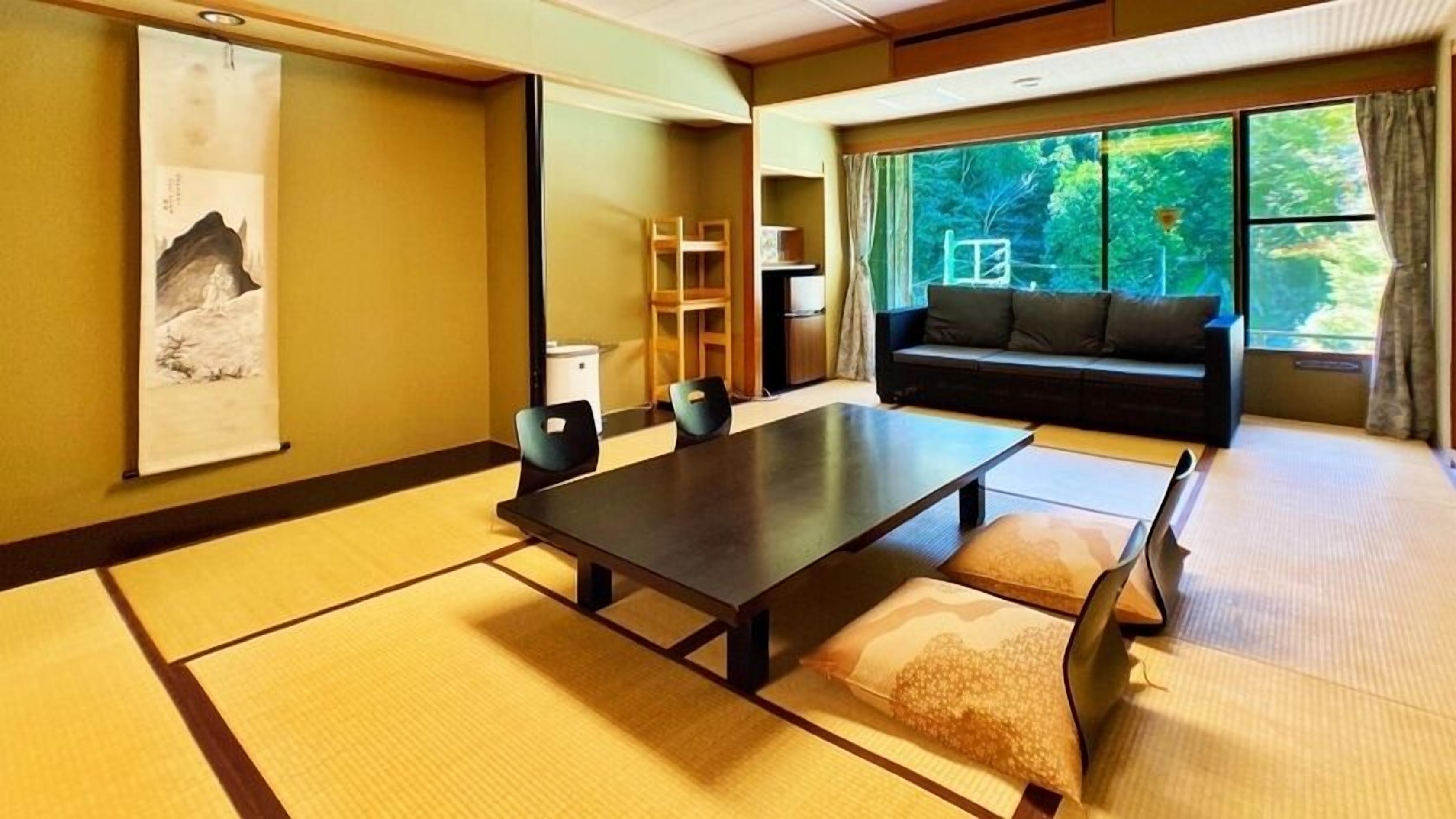Una habitación tradicional japonesa con suelo de tatami, una mesa baja y un sofá.