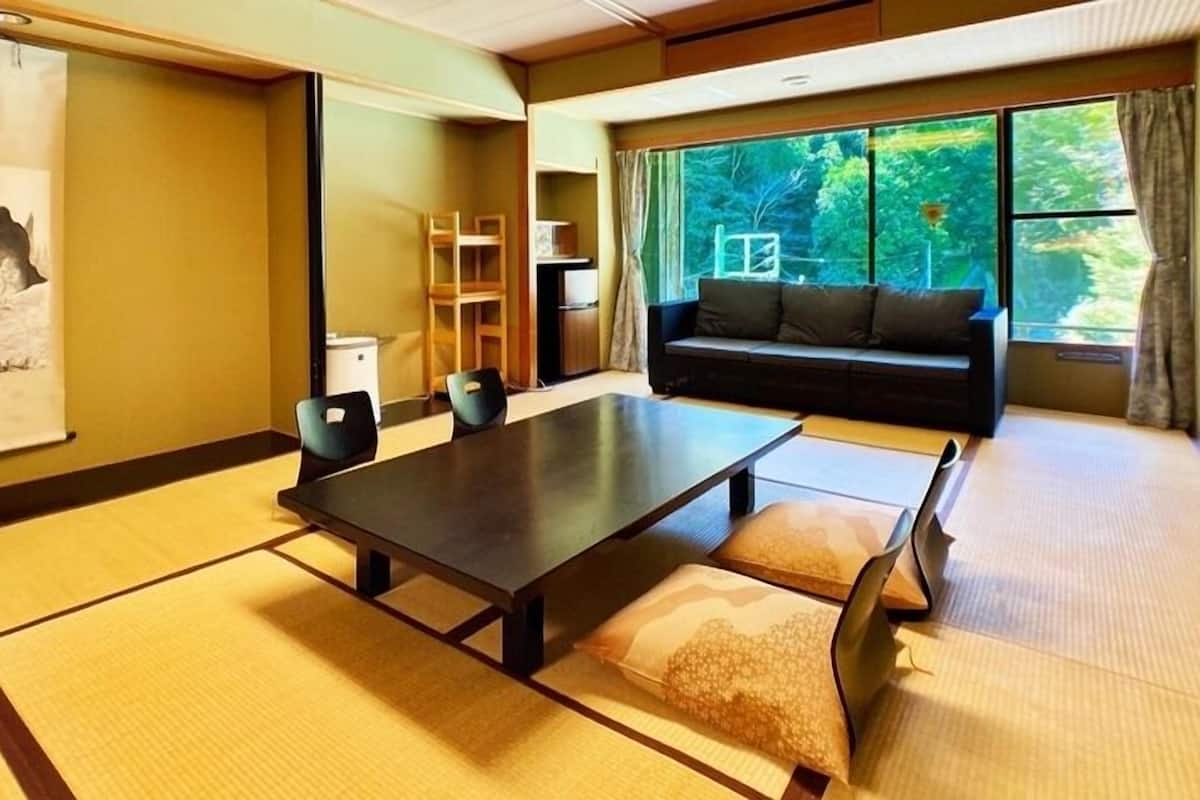 Una habitació tradicional japonesa amb fusteria de tatami, una taula baixa i un sofà.