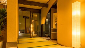 Ein traditionelles japanisches Interieur mit Tatami-Böden, einer Schiebetür und einer modernen Leuchte.