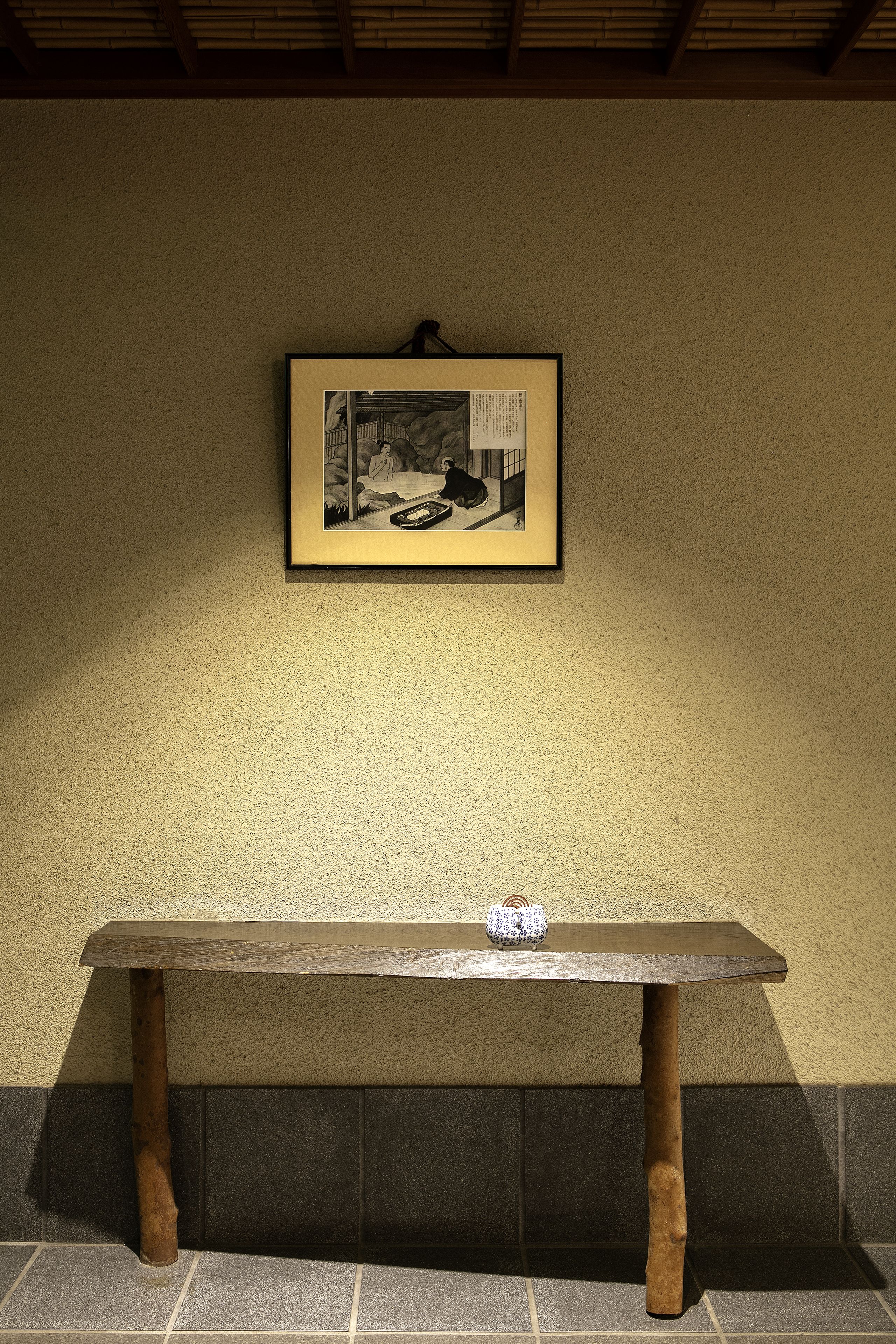 Un banc avec un tableau encadré accroché au mur derrière.