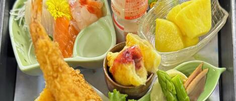Een dienblad met diverse gerechten, waaronder sushi, sashimi en een fles saus.